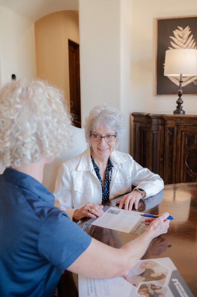 Care manager patiently explaining a care plan to a senior client at home.