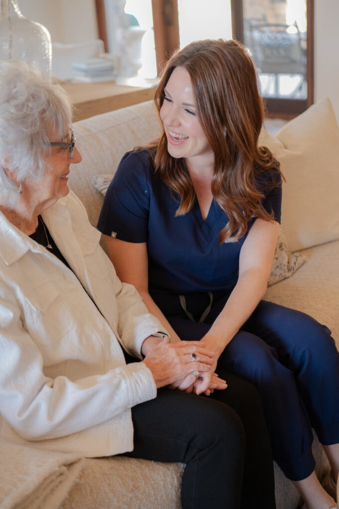 Caregiver and senior client having a conversation, both smiling and happy.