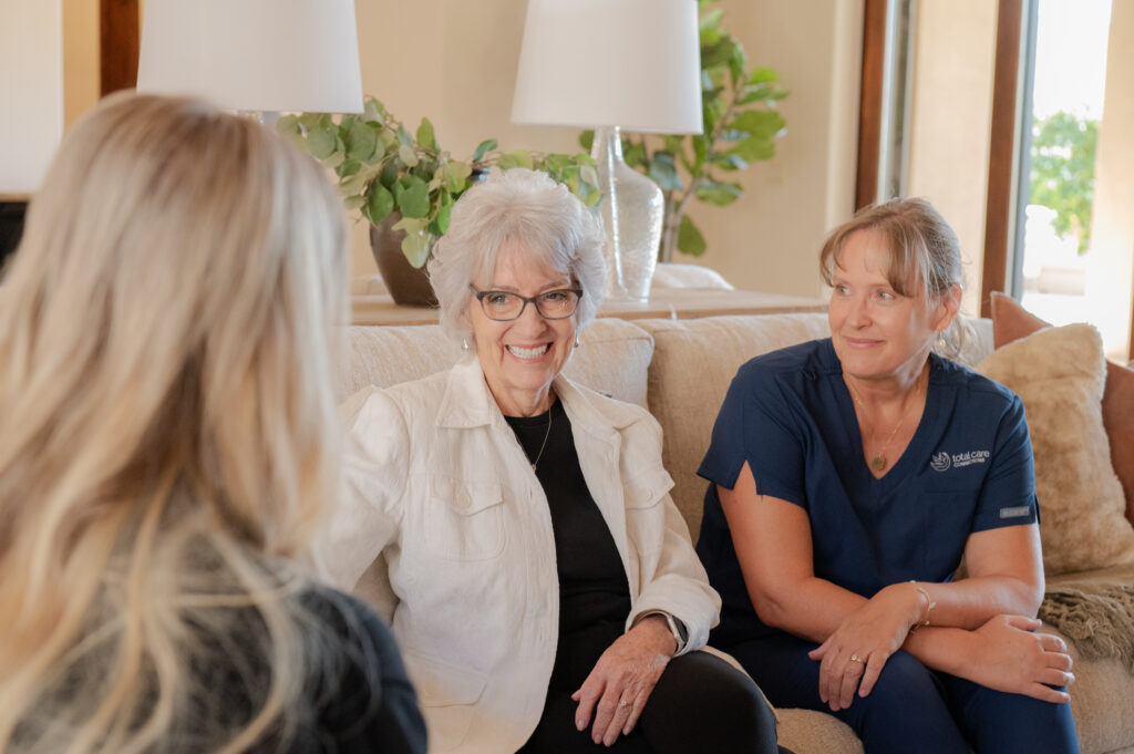 Two caregivers communicating with a senior client, all smiling and happy.